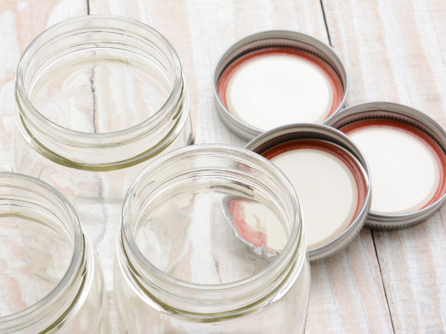 Three canning jars with 3 lids and rings laying next to them